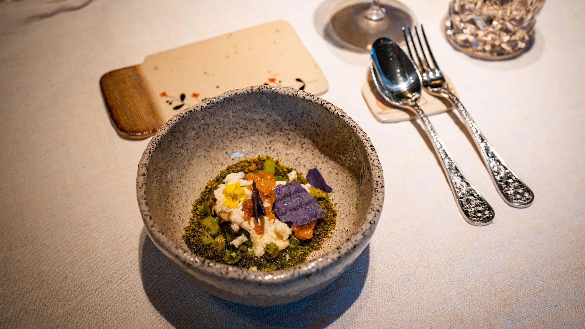 Slika majhne sklede hrane s priborom in kozarcem ob strani.