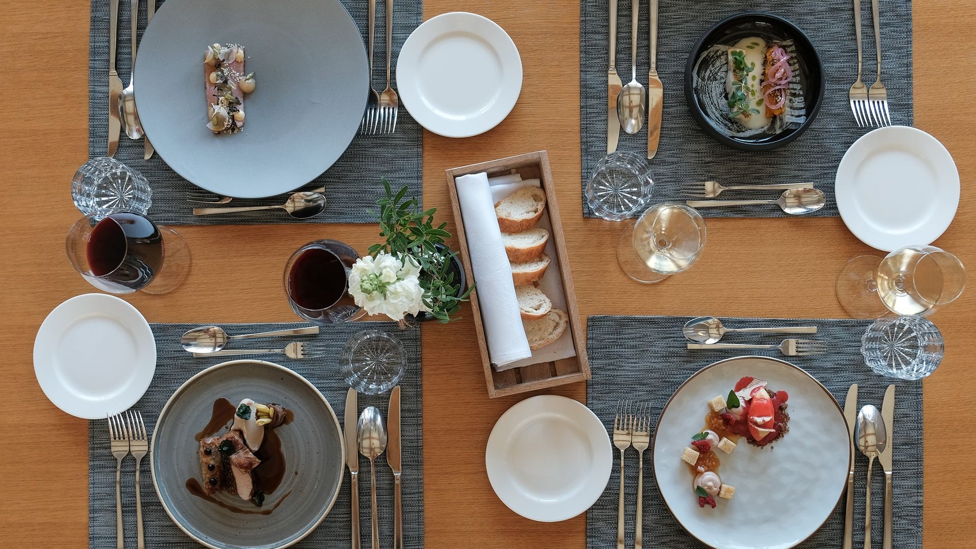 Fotografija štirih jedi s košaro za kruh na sredini.